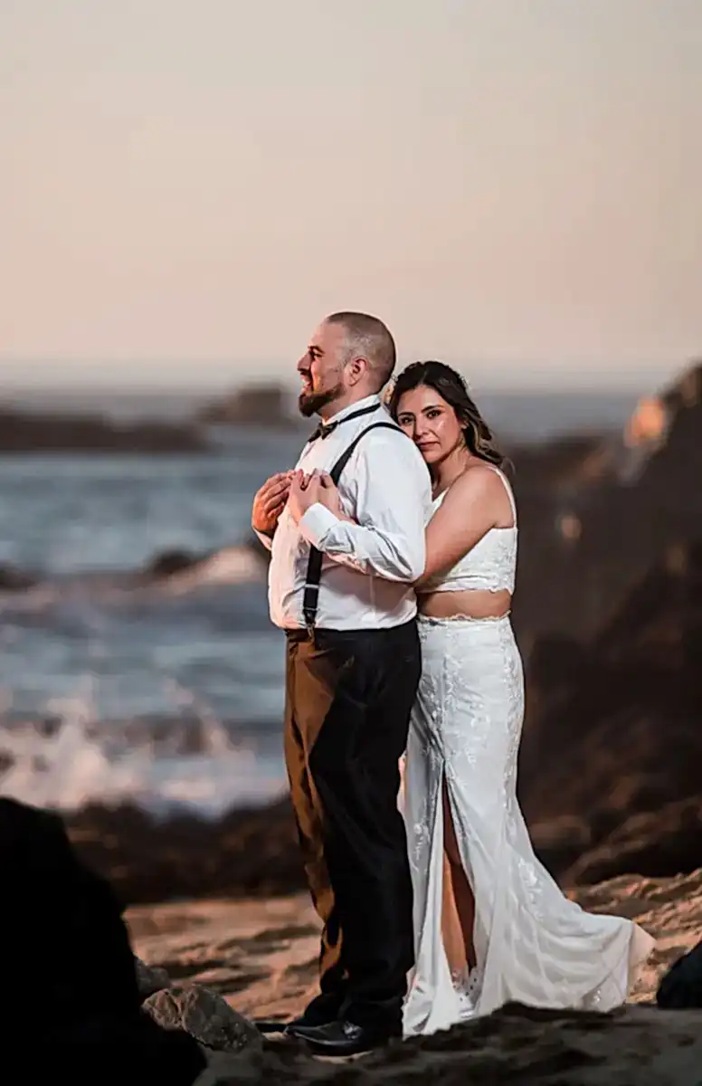 Foto de matrimonio parados frente al mar